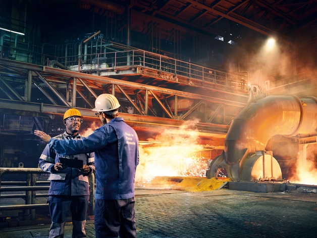 Dos ingenieros conversan en una fábrica de metal.